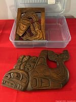 Both carved wood plaques together in bin and on table