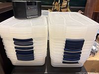 Two stacks of 16 shallow translucent storage boxes with navy latches, Sony clock radio sitting on top