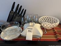 Full view of knives in stand, wine glasses, warming dish, lattice bowl, glass bowl and plates