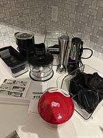 Overall view showing electric kettle, hand blender parts, mandoline blades, red gadget, storage bins