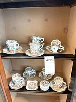 All cup-and-saucer pairs and trinket dishes displayed on cabinet shelves