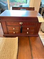 Front view of cherry finish wood jewelry box showing two drawers, lock and tassel key