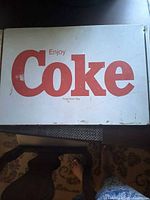 Front view of rectangular "Enjoy Coke" sign showing overall design and wear