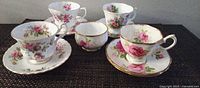 Front view of 4 teacup and saucer sets with sugar bowl