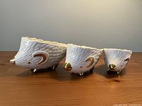 Three ceramic hedgehog measuring cups side view showing gold-tone accents