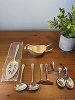 All nine pieces displayed: sealed cake server, gravy boat, two long spoons, two short spoons, three pushers