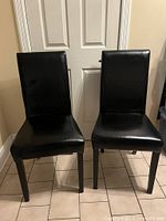 Front view of two matching black bonded leather Parsons chairs