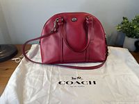 Front view of Coach deep pink dome satchel with strap on dust bag
