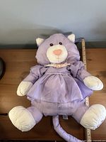 Front view of purple Puffalump cat plush beside ruler