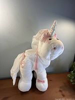 Full view of white Puffalump unicorn plush standing on table