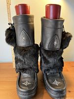 Front view of both boots on stands showing leather, fur, beadwork and overall condition