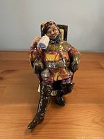 Front view of seated gentleman figurine holding mug