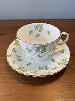 Teacup on saucer showing shamrock pattern, swirl design and gold trim