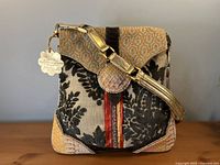 Front view of Spencer & Rutherford handbag showing materials, flap, strap and attached charm