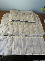 Two beige cloth storage rolls with stitched utensil slots