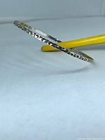 Full view of sterling silver bangle showing diamond-cut pattern