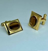 Frontal view of both cufflinks showing tiger's eye stones and gold-tone finish