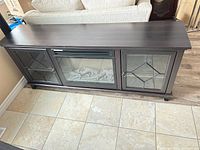 Front view of dark brown media console showing fireplace insert and two glass cabinet doors