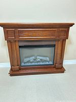 Front view of electric fireplace mantel showing glass panel and faux logs