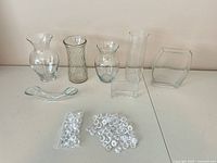 All seven glass vases, acrylic gems in bag and loose on table
