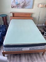 Overall view of bed with topper, mattress, frame, headboard