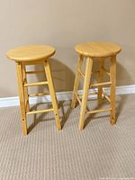 Two solid wood round-top stools side by side