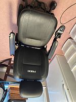 Top view of black vinyl Pride power wheelchair seat, joystick visible