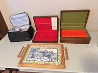 All four items arranged on table: cooler bag, two flatware boxes open, tile serving tray