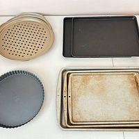 All eight pieces grouped: round pizza pans, black trays, silver sheets, tart pan
