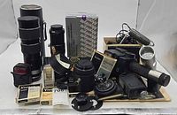 Group shot of all camera items including lenses, filters, Polaroid pack, sensor, meter