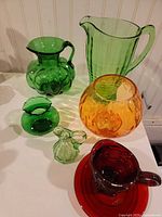 overview of seven colored glass items on table