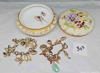 Overall lot: porcelain jar with lid removed, two charm bracelets