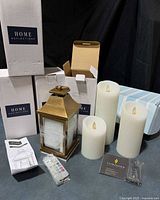 Group shot showing four Home Reflections boxes, one unboxed lantern, three Luminara candles, remotes and paperwork