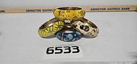 Four enamel rhinestone clamp bracelets stacked, lot number visible