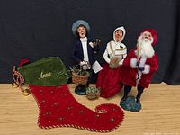 Group view of three caroler figurines and embroidered stocking