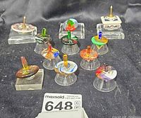 Group view of all eleven tops on clear acrylic display bases