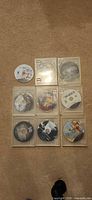 All nine PS3 discs in clear sleeves plus one loose disc visible on carpet