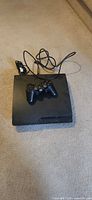 Top view of PlayStation 3 Slim with controller and cords