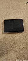 Top view of black PlayStation 3 Super Slim console on carpet