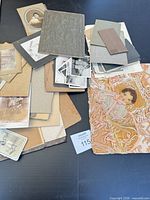 Assortment of cabinet cards, loose photos and textile artwork laid out
