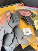 Stack of foam-core face paddles, grey backing supports and yellow sign in background