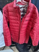 Full view front of red Columbia puffer jacket on hanger
