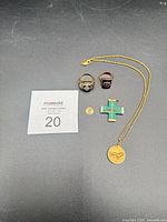 All six jewelry pieces laid out: two rings, chain with Leo pendant, St Jude pendant, malachite cross