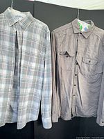 Two shirts: plaid and grey chambray hanging