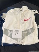 White Nike jacket on top of navy and black jackets with lot card visible