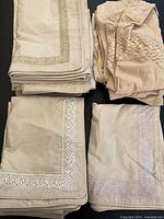 Stacks of tan pillow shams with different lace edges, bolster covers to side