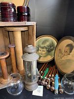 Overview showing crate, large spools, bobbins, framed photos, glass globes, lantern