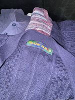 Top view showing navy cable-knit sweater label, marled sweater edge, and navy henley pullover