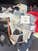 Pile of assorted clothing accessories including belts, gloves, scarf, headband in bag