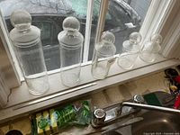 All five glass canisters lined up on windowsill